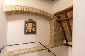 A staircase with a stone archway, a wooden beam, and a framed picture on the wall.
