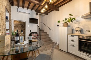 A modern kitchen with a glass table, wine bottles, a refrigerator, and a staircase.