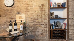 A brick wall with a clock, a wine rack, and shelves with books and decorative items. - Apartment 'Domus Vestae' with Wi-Fi and Air Conditioning (San Gimignano)