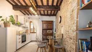A kitchen with a dining table, chairs, a refrigerator, and a brick wall. - Apartment 'Domus Vestae' with Wi-Fi and Air Conditioning (San Gimignano)