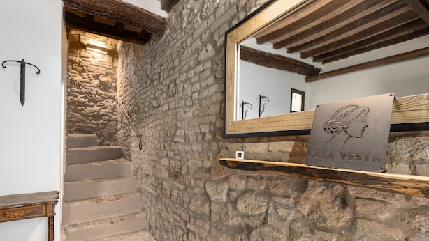 A stone staircase leading to a wooden beam ceiling, a mirror with a framed artwork, and a sign reading 'CASA VESTA'. - Apartment 'Domus Vestae' with Wi-Fi and Air Conditioning (San Gimignano)