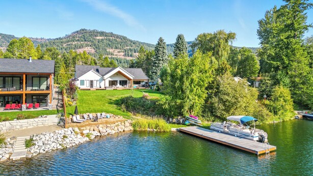 A lakeside property with a dock, a swimming pool, and a large house with multiple rooms.