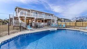 Ein zweistöckiges Haus mit Swimmingpool, Außenbereich und einem umzäunten Deck.