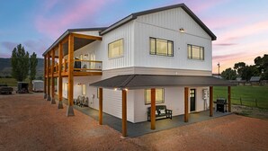 Une maison à deux étages avec un patio couvert, un balcon et un garage.