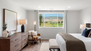 Une chambre avec une grande fenêtre, un lit, une commode et une chaise.