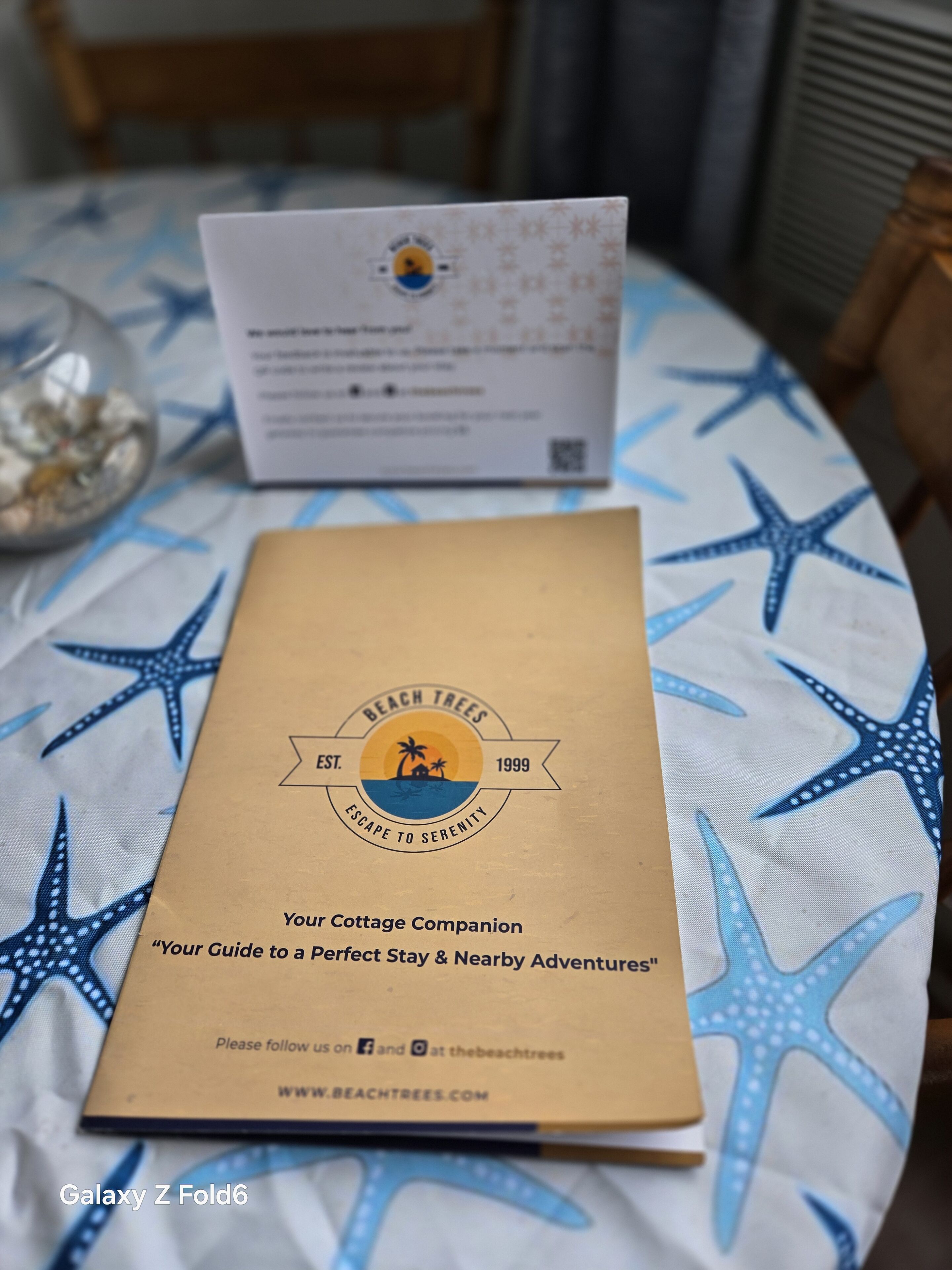 Un folleto titulado 'Your Cottage Companion' sobre una mesa con estampado de estrella de mar.
