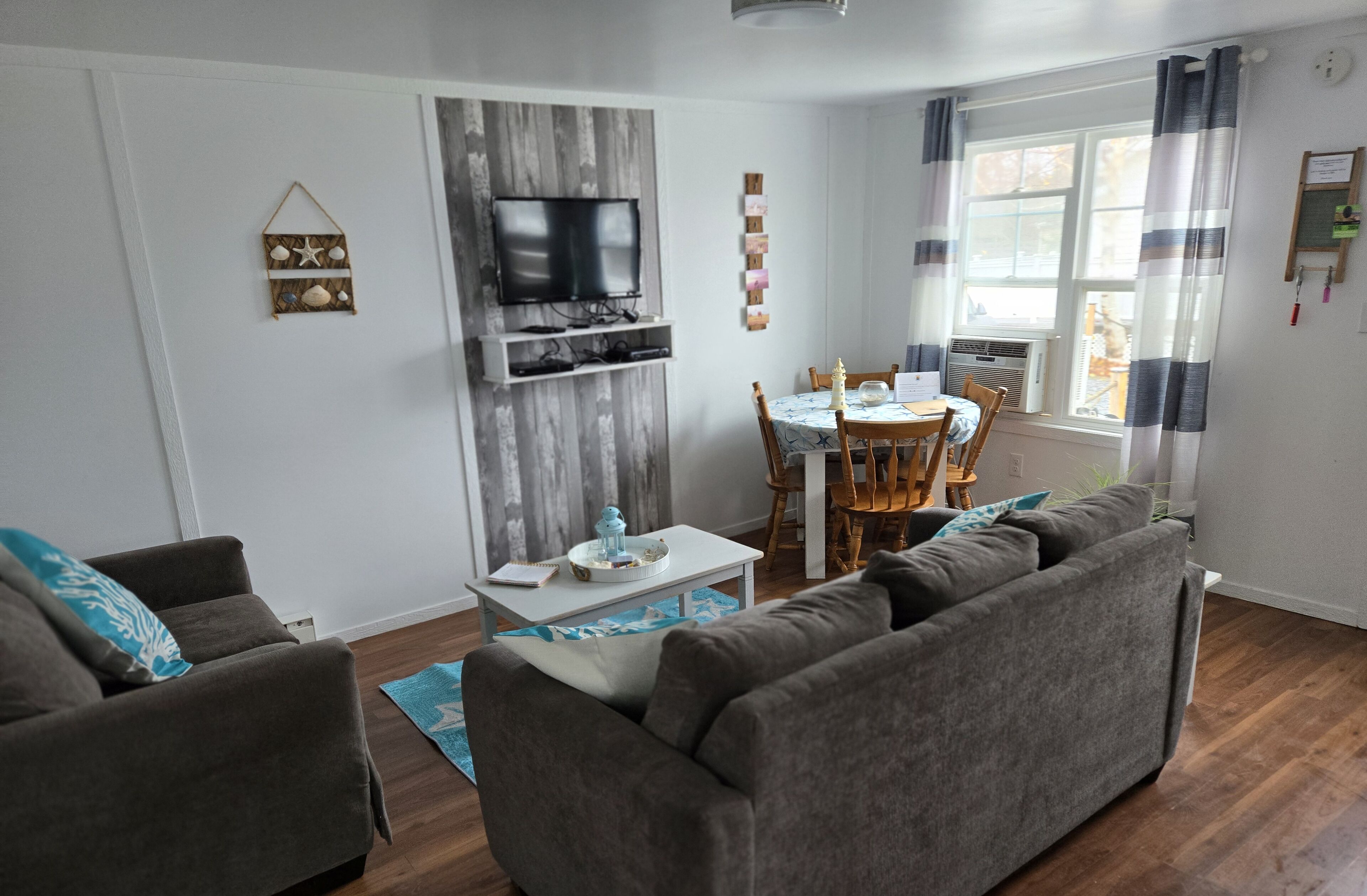 A living room with a TV, a dining table with chairs, and a sofa.