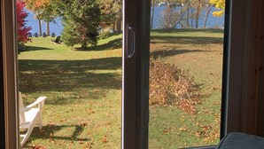 Huone, jossa on liukuovi, joka johtaa ulos vehreälle, puita kasvavalle alueelle, ja josta avautuu näkymä vesistöön.
