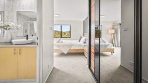 A modern bedroom with a large window, a bed, and a bedside table. - Tree Top Views - 4 Bedroom House (Rosetta)