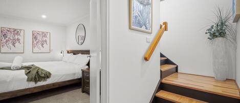 A bedroom with a bed, a nightstand, a dresser, and a staircase with wooden steps.