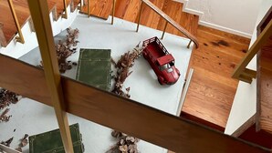 Una scala in legno con un'automobilina rossa e decorazioni vegetali sulla piattaforma.
