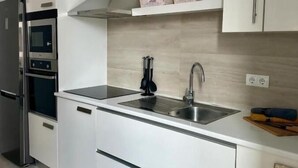 Una cucina moderna con mobili bianchi, un lavandino in acciaio inossidabile e un forno integrato.