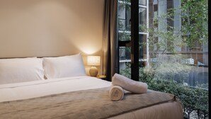 A hotel room with a bed, a lamp, and a view of a building and trees through the window. - StayCentral - Oasis on Mackenzie (Melbourne)