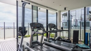 A modern gym with treadmills, a stationary bike, and weight equipment. - StayCentral - Oasis on Mackenzie (Melbourne)