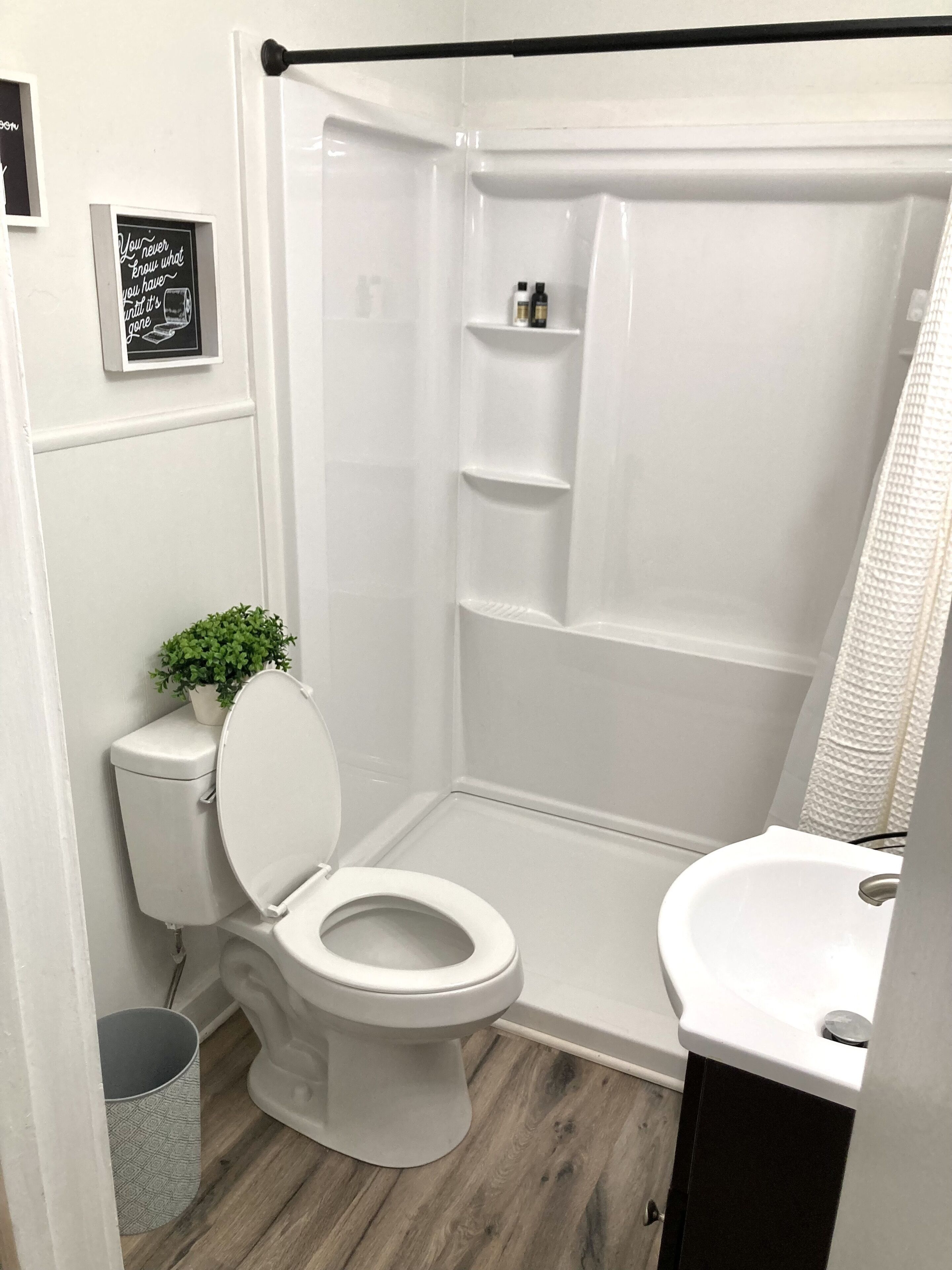 Une salle de bain comprenant des toilettes, un lavabo, une douche et une petite étagère avec des articles de toilette.