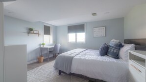 A bedroom with a bed, a desk, and a chair.