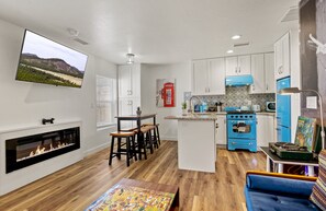 Eine moderne Küche mit weißen Schränken, einem blauen Herd und einem Wand-Fernseher.