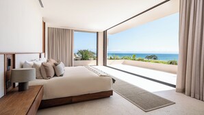 Een moderne slaapkamer met een groot bed, een nachtkastje en uitzicht op de oceaan.