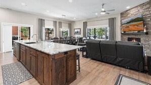 Une cuisine spacieuse dotée d’un grand îlot central, d’un coin repas et d’un salon confortable avec une cheminée.