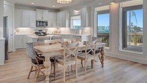 Una cocina amplia con armarios blancos, una isla central y un comedor con sillas de madera.