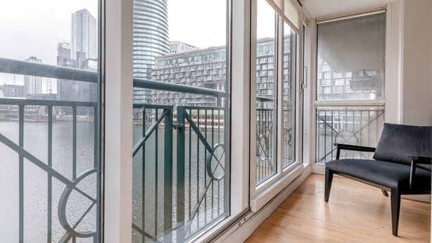 Ein geräumiges Zimmer mit großen Fenstern, die auf einen Fluss und die Stadt hinausblicken.