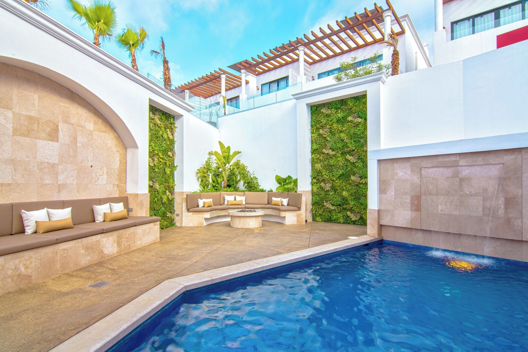 Area piscina con angolo relax integrato, una pergola e vista sull'architettura dell'edificio.