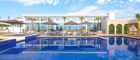 Alberca al aire libre, sombrillas en la alberca y camastros