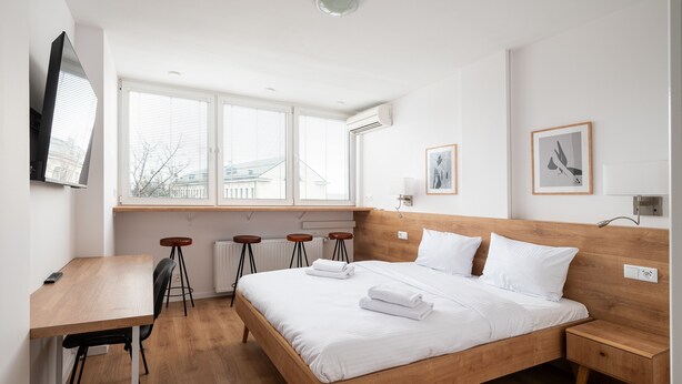 Un dormitorio con una cama de madera, un escritorio y una ventana con persianas.