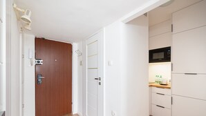 Una cocina moderna con armarios blancos, microondas y suelo de madera.