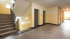 Un pasillo con escalera, puertas y una lámpara.