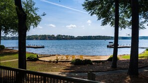 A lakeside view with a dock, chairs, and a boat.