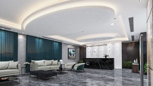 A modern hotel lobby with a curved ceiling, a marble floor, a reception desk, and seating area with sofas and armchairs. - Pearl Hotel (Dhaka)