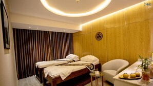 A hotel room with a bed, a small table, a chair, and a counter with a plant and a fruit display. - Pearl Hotel (Dhaka)