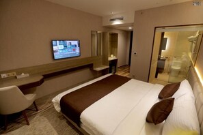 A hotel room with a bed, a desk, a TV, and a mirror. - Pearl Hotel (Dhaka)