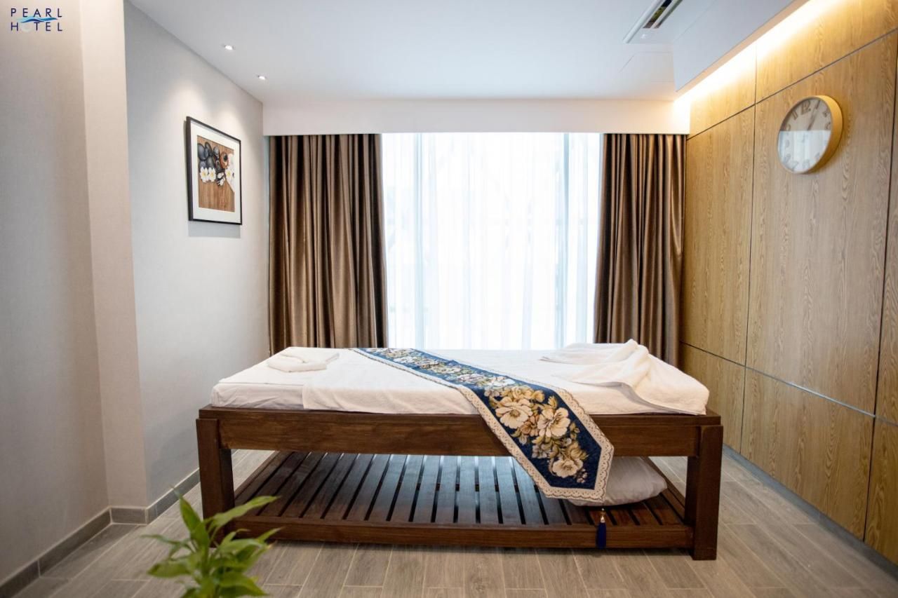 Quarto de hotel com cama, cortinas, relógio e quadro na parede.
