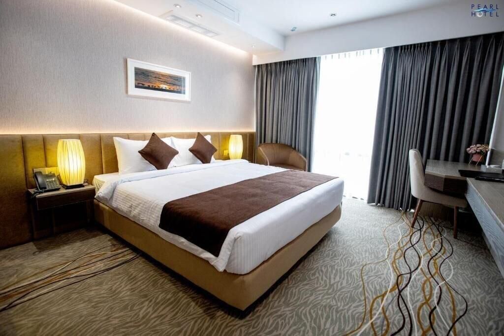 A hotel room with a large bed, a desk, a chair, and a view of the outdoors.