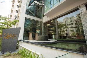 A modern hotel with a prominent sign, large windows, and a pool area. - Pearl Hotel (Dhaka)