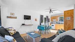A modern living room with a sofa, a coffee table, and a dining area with a table and chairs. There is a kitchen visible in the background. - Drift Wood, Spacious 2 BRs, Living, Kitchen, Full Bathroom & a Patio  (York)