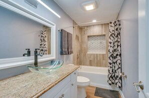 Bathroom features a glass bowl sink, a toilet, and a bathtub.