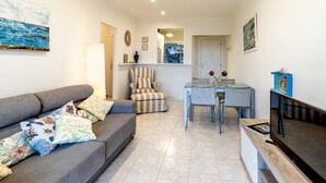 A living room with a grey sofa, striped armchair, and a dining table with chairs. - Les Tonyines 67 - Apartment with views and terrace (Llança)
