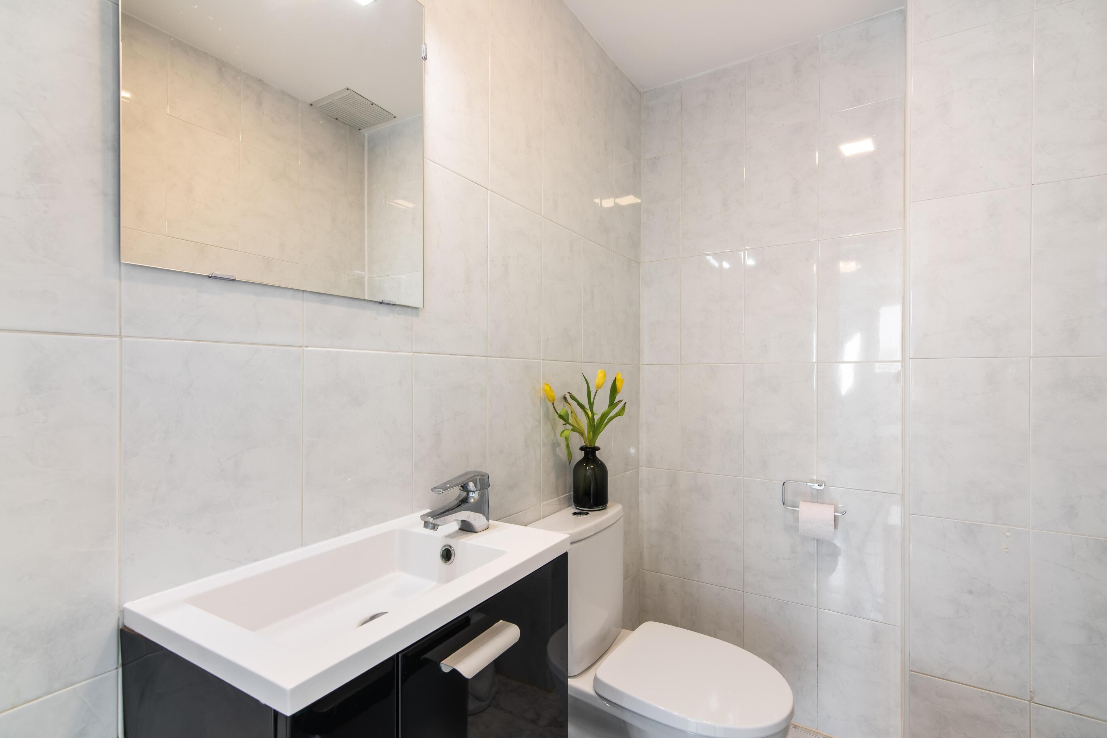 A modern bathroom with a white sink, a toilet, and a mirror.