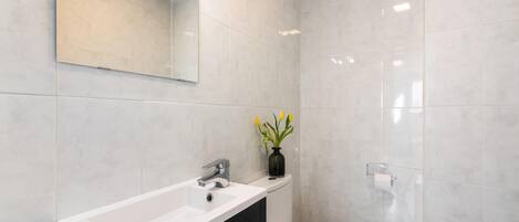 A modern bathroom with a white sink, a toilet, and a mirror.
