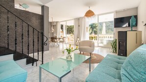 Ein modernes Wohnzimmer mit Treppe, einer Couch, einem Glastisch und einem Fernseher.