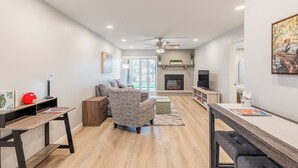Una sala de estar moderna con chimenea, ventilador de techo y televisor.
