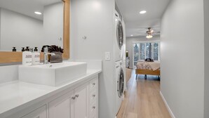 Un baño moderno con un espejo grande, tocador blanco y ventilador de techo.
