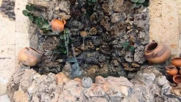 Un jardin de rocaille agrémenté d’un élément aquatique et de poteries.