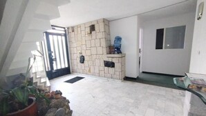 Un vaste espace de vie agrémenté d’un mur en pierre, d’un distributeur d’eau et d’une plante en pot.