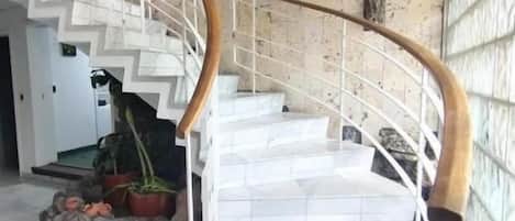 Una escalera de mármol con barandilla de madera que conduce a una plataforma.