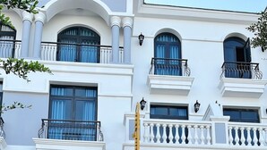 Un edificio a più piani con facciata bianca, balconi con ringhiere nere e un caffè a livello strada.