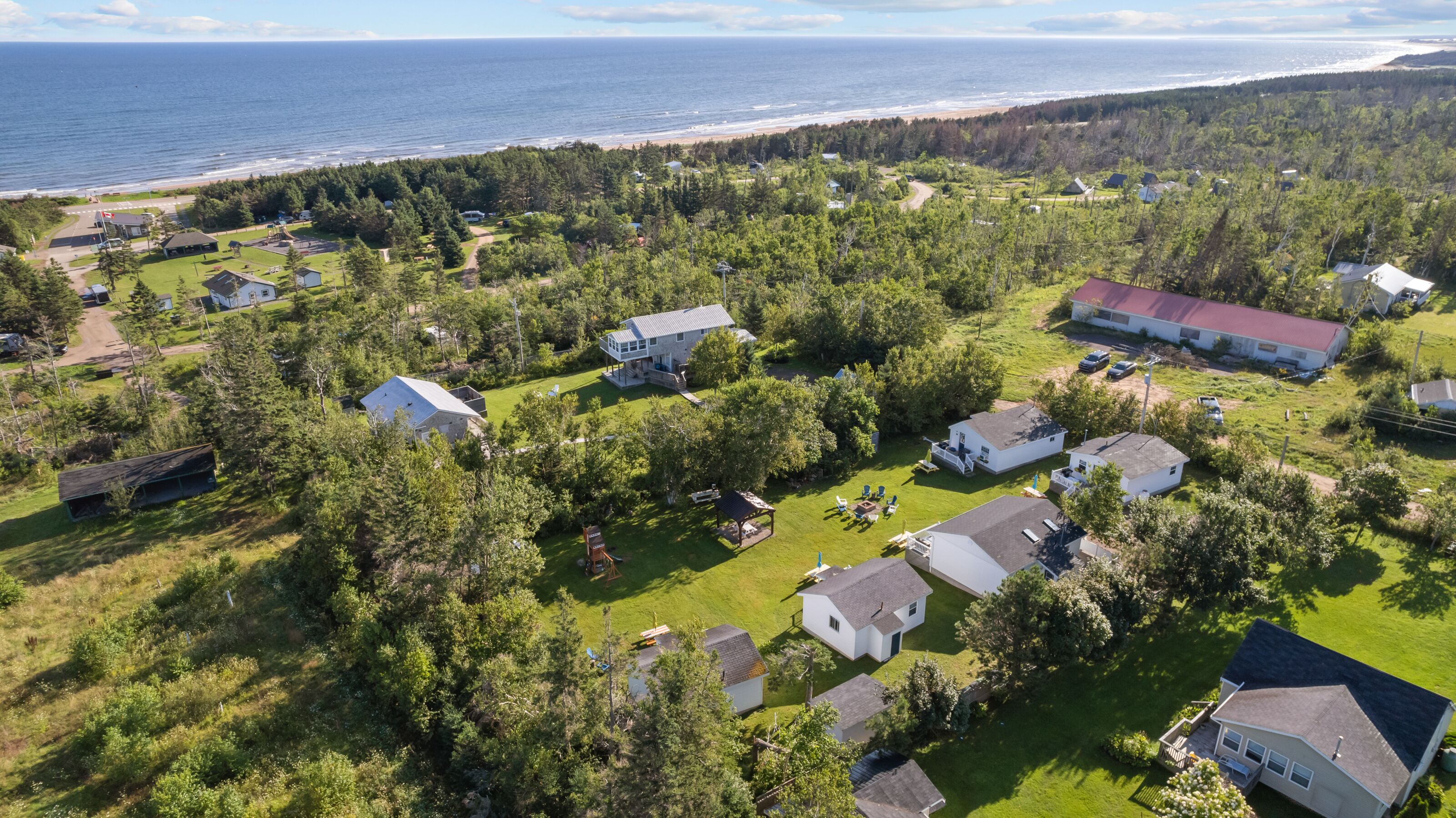 Oversigtsbillede af et boligområde med huse, grønne plæner og en strand i baggrunden.